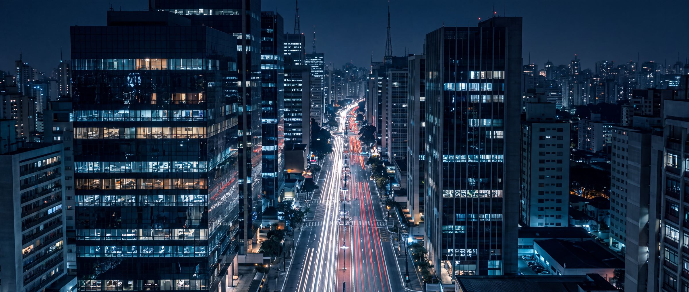 Avenida corporativa de São Paulo à noite vista do alto, com os escritórios iluminados